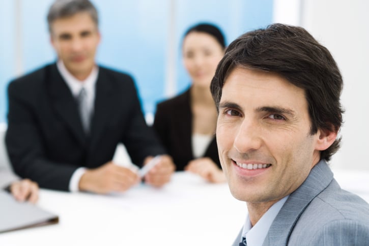 Businessman in meeting, smiling at camera