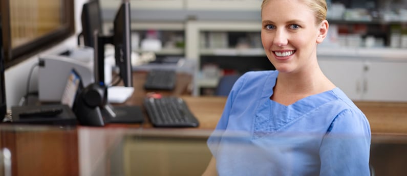 A smiling medical assistant at her desk.